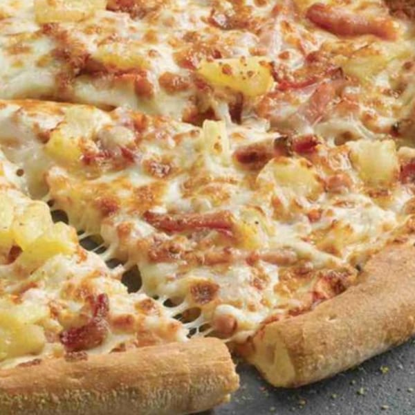 Close-up of a Goodfellas Pizza and Wings Hawaiian pizza with melted cheese, ham, and pineapple.