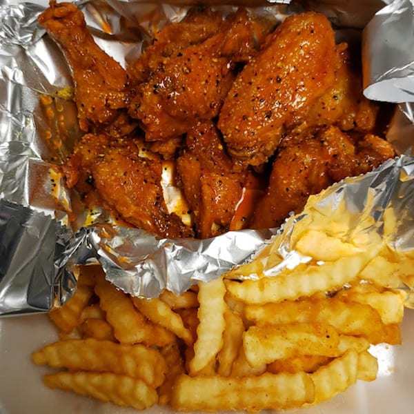Goodfellas Pizza and Wings' spicy chicken wings and crinkle-cut fries in a foil-lined container.
